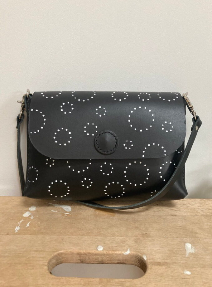 handmade-black-leather-cross-body-bag-silver-hardware-circle-spots-plain-leather-strap-wooden-stool-front-view